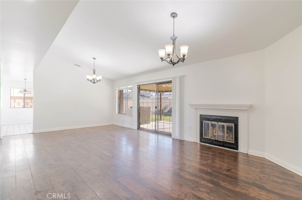 4906 Pacifica Avenue Palmdale, CA 93552 - Photo 12 of 36 an empty room with wooden floor chandelier and glass door