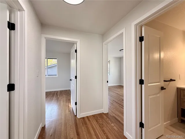 a view of a hallway with wooden floor and a bathroom