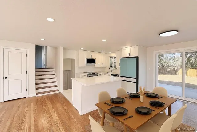 a kitchen with a refrigerator a stove and a dining table with wooden floor