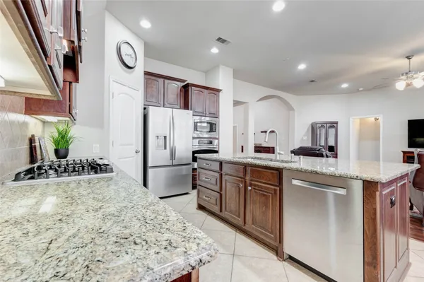 a kitchen with stainless steel appliances kitchen island granite countertop a refrigerator and a sink