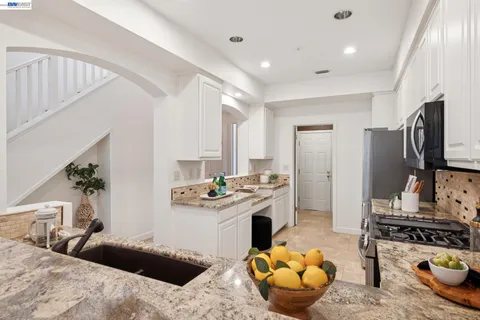 a kitchen with granite countertop stainless steel appliances and white cabinets