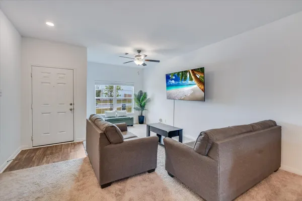 a living room with furniture a ceiling fan and a rug