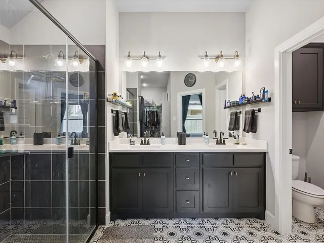 a bathroom with a double vanity sink mirror and shower