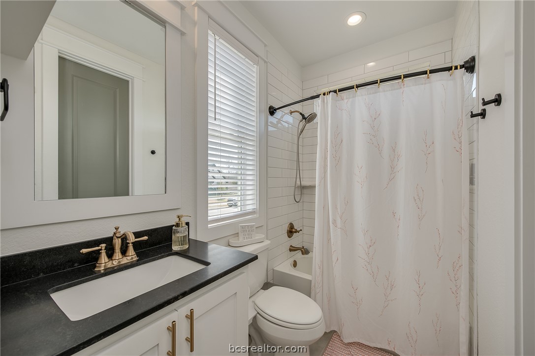 3317 Stone Leigh Lane Bryan, TX 77808 - Photo 17 of 30 a bathroom with a granite countertop sink toilet a mirror a vanity and shower