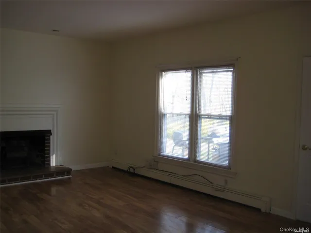 an empty room with wooden floor fireplace and windows
