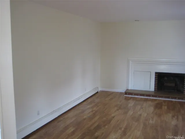 a view of empty room with wooden floor and fireplace