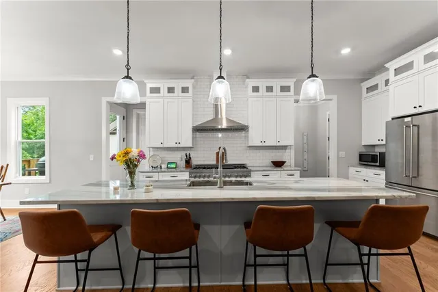 a kitchen with stainless steel appliances granite countertop a sink a stove and a wooden floors