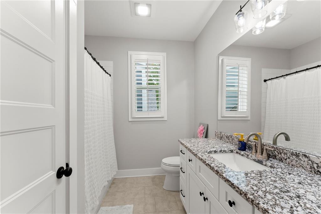 4847 Destitute Way Gainesville, GA 30506 - Photo 49 of 67 a bathroom with a granite countertop sink a toilet and a mirror
