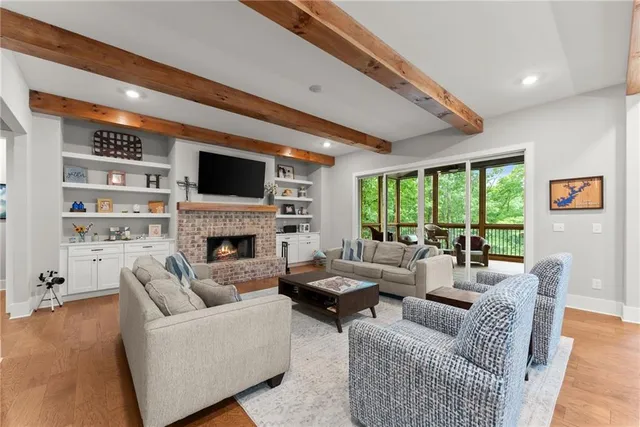 a kitchen with stainless steel appliances granite countertop a sink a stove a refrigerator and white cabinets with wooden floor