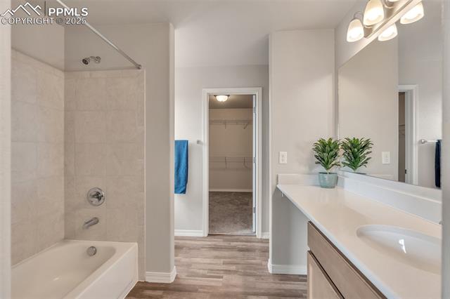 11053 Avena Road Peyton, CO 80831 - Photo 19 of 27 Bathroom with vanity, wood finished floors, shower / bathtub combination, and a spacious closet