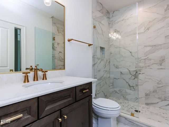 a bathroom with a granite countertop sink a toilet and shower