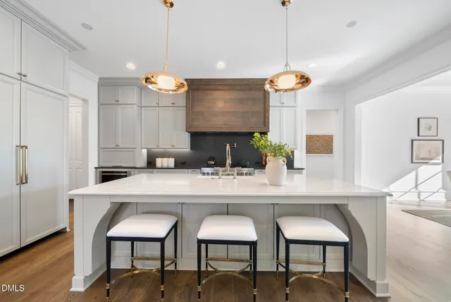 a large white kitchen with a large island in the center