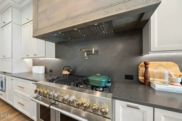 a kitchen with stainless steel appliances granite countertop a sink a stove and white cabinets