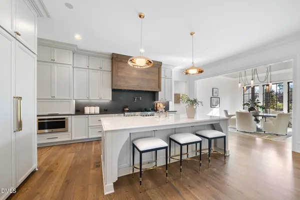 a kitchen with stainless steel appliances granite countertop a sink a stove a refrigerator and island with wooden floor