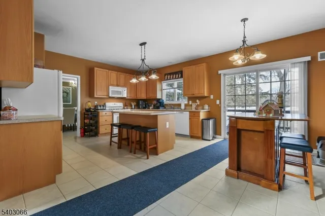 a kitchen with stainless steel appliances granite countertop a refrigerator a oven a sink a dining table and chairs with wooden floor