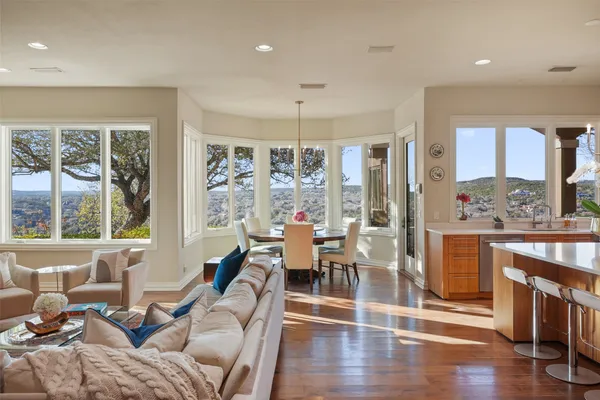 a living room with furniture a large window and wooden floor