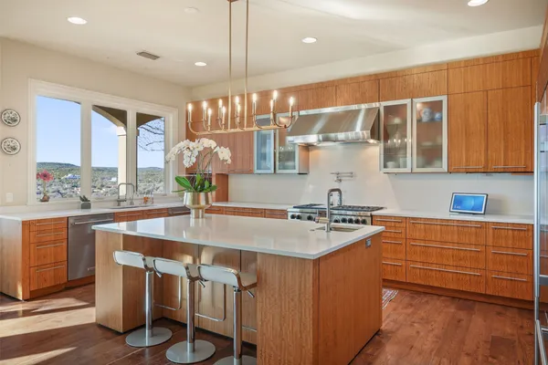 a kitchen with kitchen island granite countertop a table chairs stove and wooden cabinets