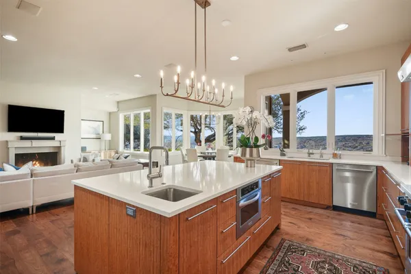a kitchen with sink stove and white cabinets with wooden floor