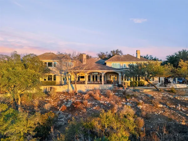 a view of a big house with a big yard and large trees