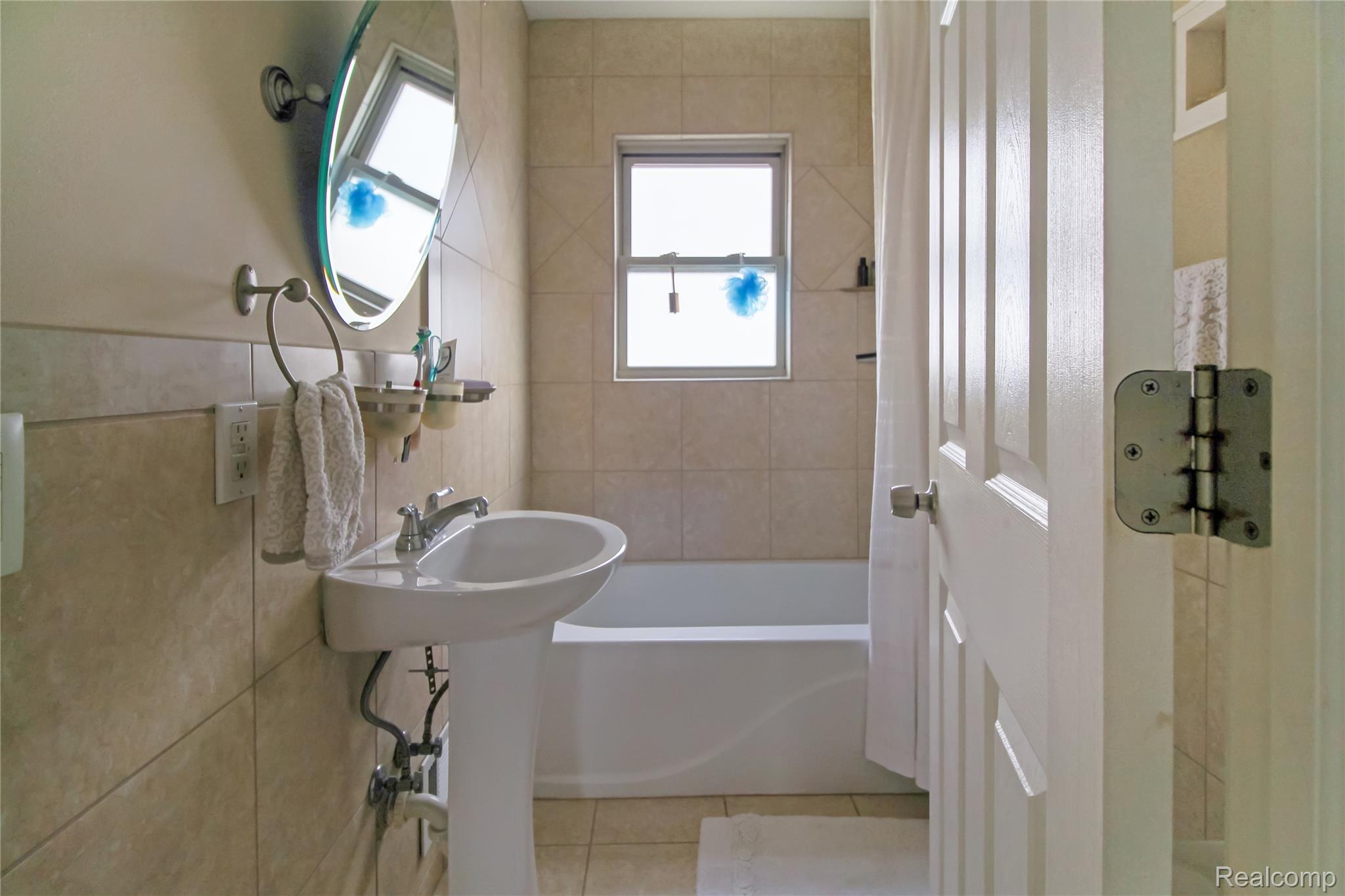 5953 Cooper Street Taylor, MI 48180 - Photo 8 of 33 Bathroom featuring a pedestal sink with a chrome faucet, a round wall-mounted mirror, and beige tile flooring
