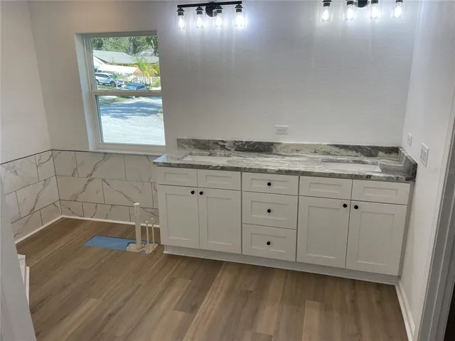 an empty room with wooden floor cabinet and windows