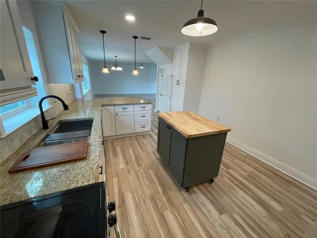 a room with kitchen island a wooden floor and a ceiling fan