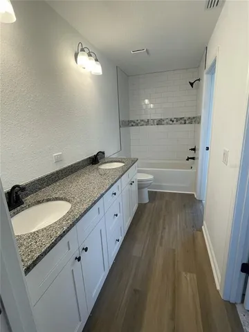 a spacious bathroom with a granite countertop double vanity sink a mirror and a shower