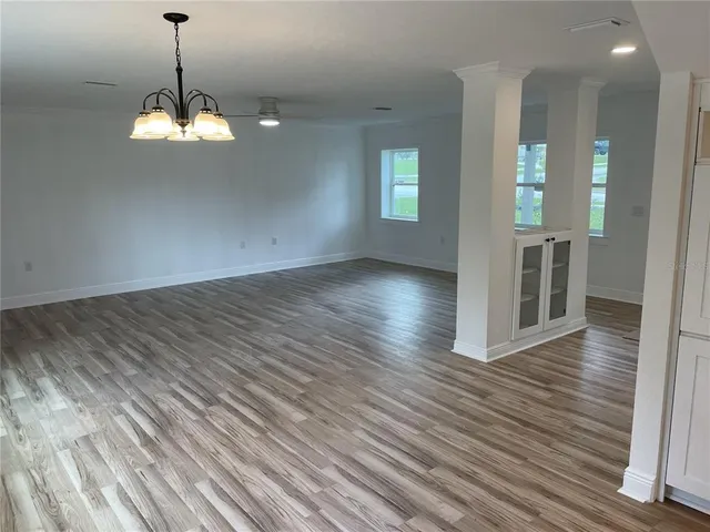 a view of a room with wooden floor chandelier and windows