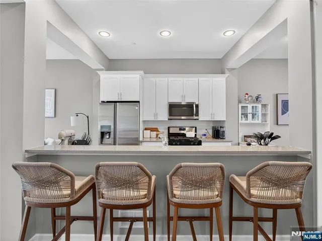 a kitchen with stainless steel appliances granite countertop a table chairs and a refrigerator