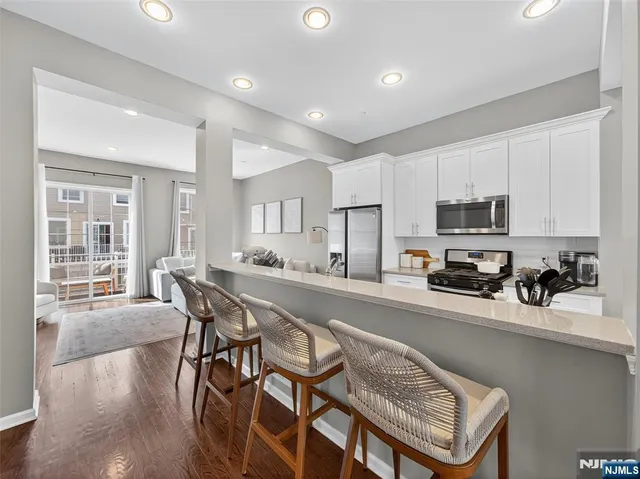 a kitchen with a sink dishwasher stove and white cabinets with wooden floor