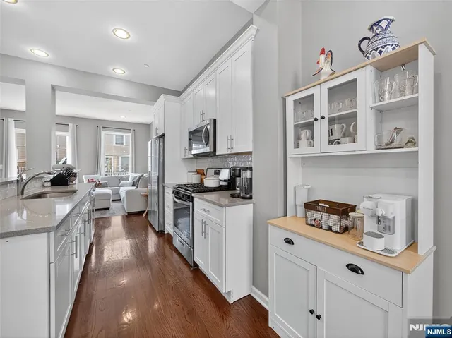 a kitchen with sink and white cabinets with wooden floor