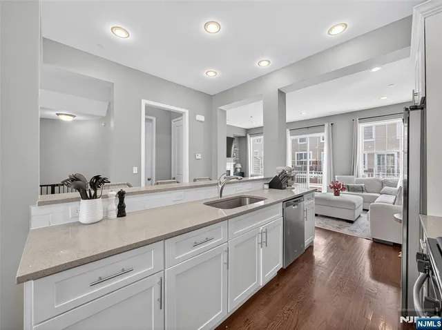 a kitchen with stainless steel appliances kitchen island granite countertop a refrigerator a stove a dining table and chairs with wooden floor