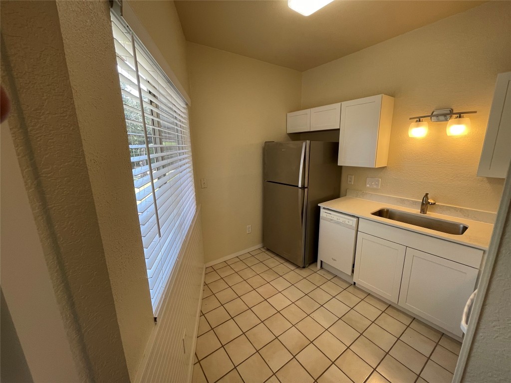 6809 West Gate Boulevard, Unit 110 Austin, TX 78745 - Photo 3 of 7 a kitchen with a refrigerator and a sink
