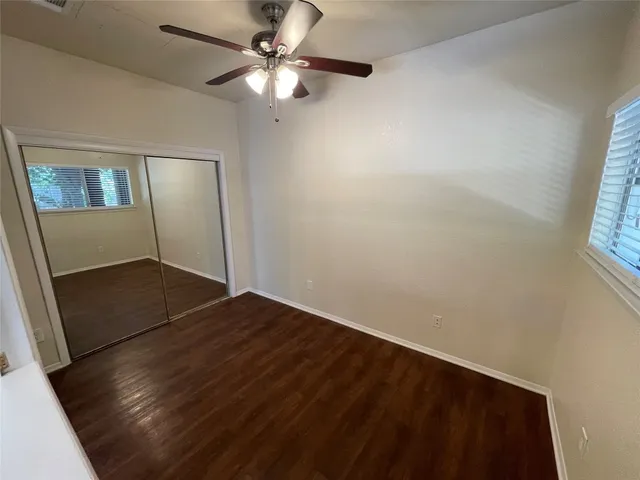 an empty room with wooden floor fan and windows