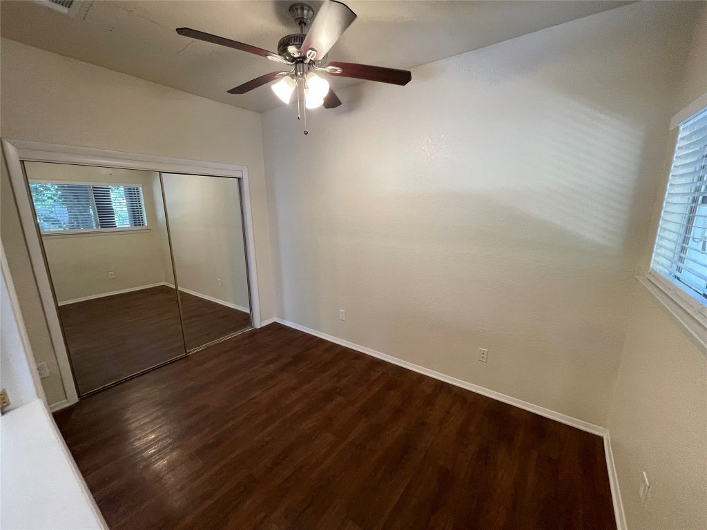 6809 West Gate Boulevard, Unit 110 Austin, TX 78745 - Photo 4 of 7 an empty room with wooden floor fan and windows