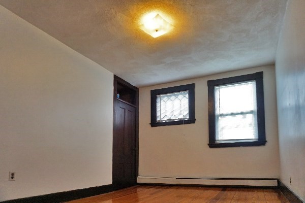 159 Brown Street, Unit 3 Waltham, MA 02453 - Photo 6 of 10 an empty room with wooden floor and windows