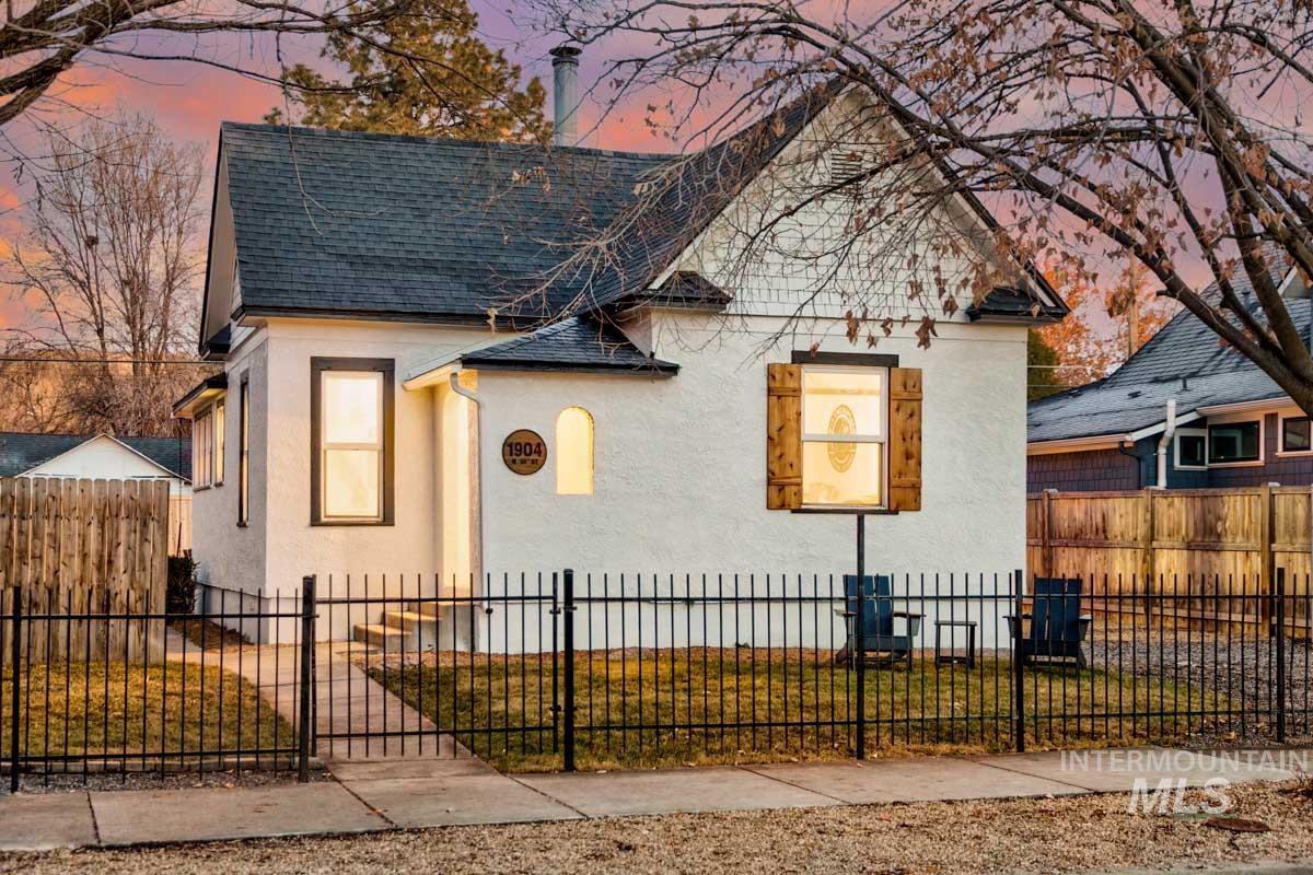 View of front of property with stucco siding, a fenced front yard, and a shingled roof