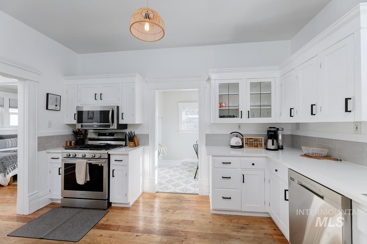 1904 North 16th Street Boise, ID 83702 - Photo 19 of 28 Kitchen with stainless steel appliances, white cabinetry, glass insert cabinets, light wood-style flooring, and hanging light fixtures