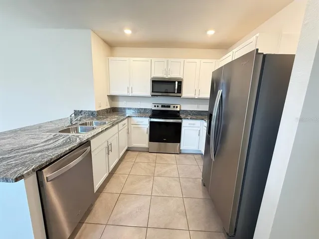 a kitchen with stainless steel appliances granite countertop a refrigerator stove and sink