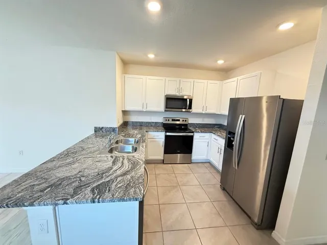 a kitchen with granite countertop a refrigerator a stove a sink and a microwave