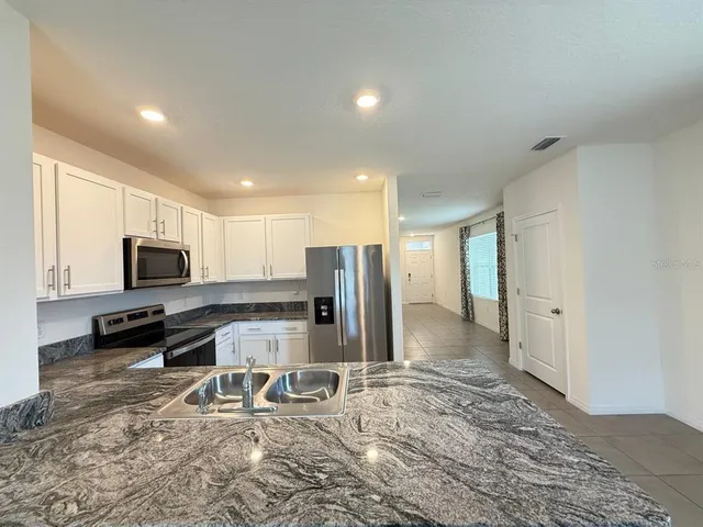 a kitchen with kitchen island granite countertop a refrigerator and a stove top oven