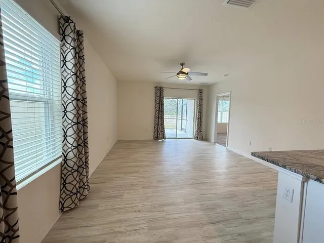 a view of an empty room with window and wooden floor
