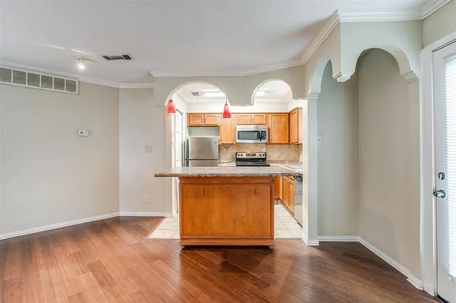 a view of kitchen with granite countertop stainless steel appliances and wooden floor