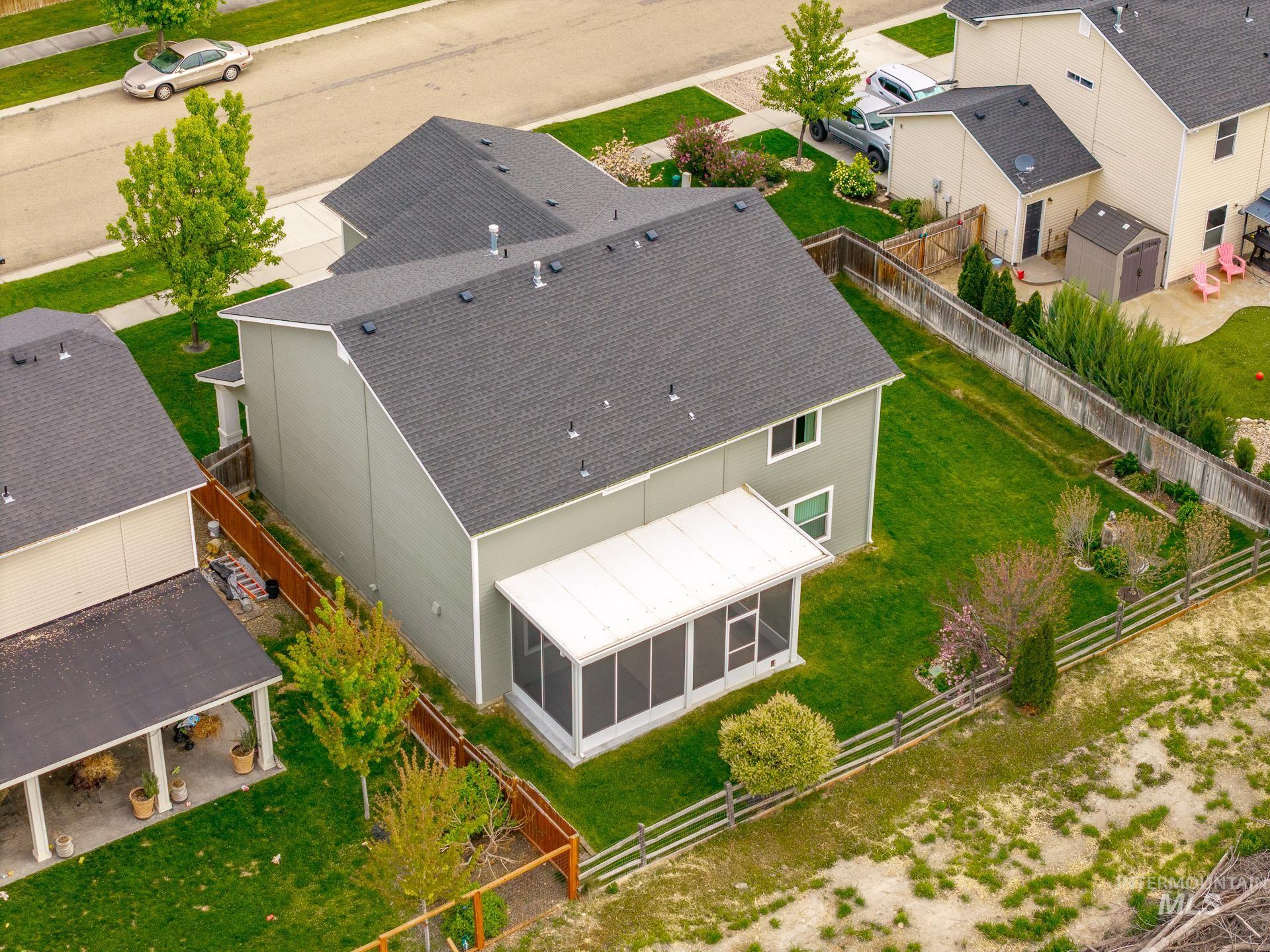 1555 Condor Drive Middleton, ID 83644 - Photo 5 of 50 Rear exterior featuring a screened porch, expansive green lawn, and a wooden privacy fence