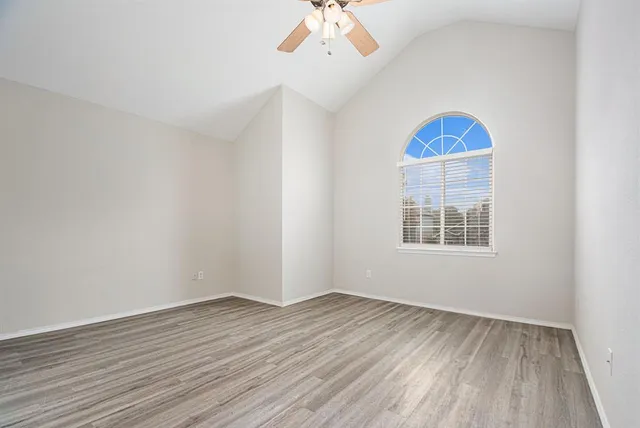 an empty room with wooden floor chandelier and windows