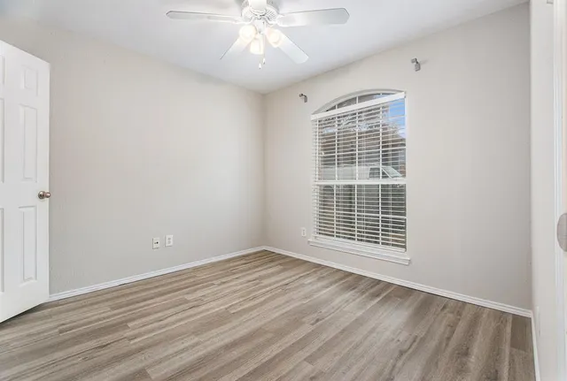 a view of an empty room with wooden floor and a window