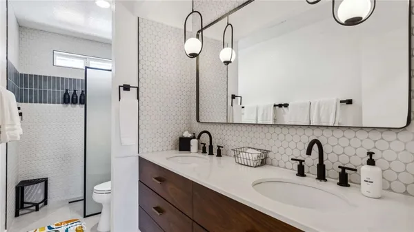 a bathroom with a double vanity sink toilet and shower
