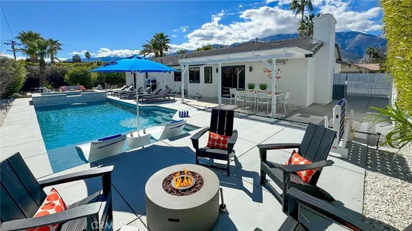 a view of a patio with table and chairs under an umbrella with a fire pit