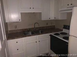 a kitchen with granite countertop white cabinets and a stove