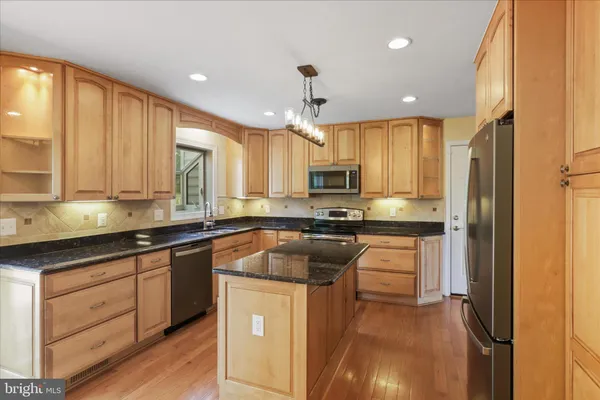 a kitchen with stainless steel appliances granite countertop a sink a stove cabinets counter space and a window